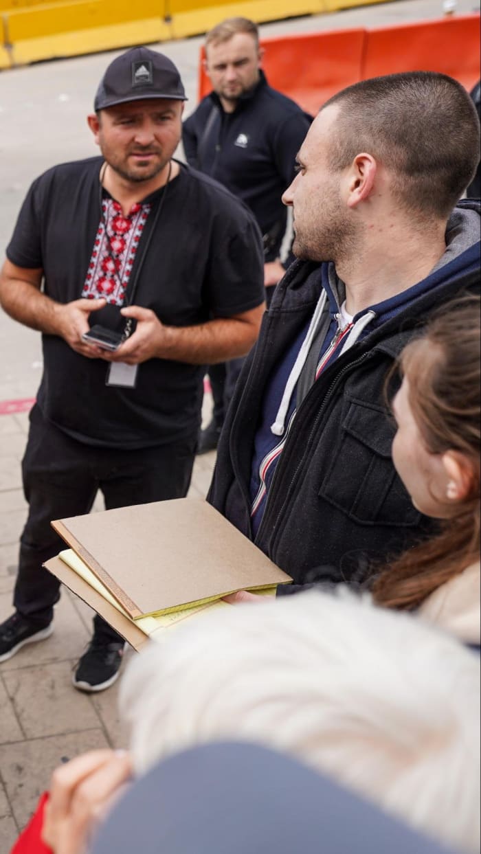 A group of Ukrainian volunteers use yellow notepads to keep a list of the asylum seekers from Ukraine waiting to enter the U.S. on March 31. Photo by Manuel Ocaño for palabra.