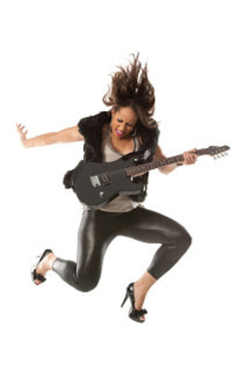 Excited female guitarist jumping with her guitar