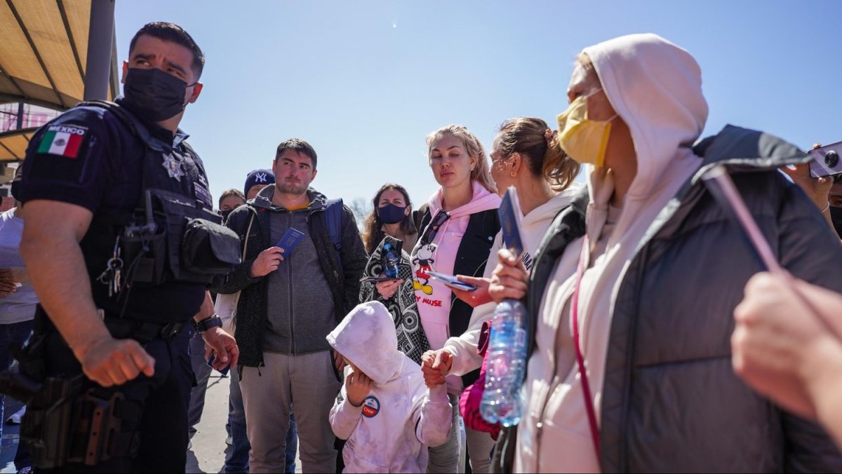 Tijuana police officer Aarón Partida assists Maryna Sokolovska, her cousin Hanna Bilonzhko, Hanna’s son Mark and the rest of the group of Ukranians traveling together to prepare for crossing into the U.S. on March 14. Photo by Manuel Ocaño for palabra.