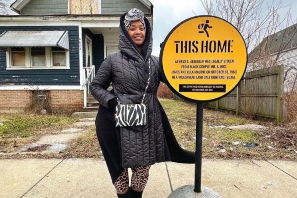 Chicago artist and activist Tonika Lewis Johnson with a sign installed to mark a house lost to a Black couple after a predatory contract sale.